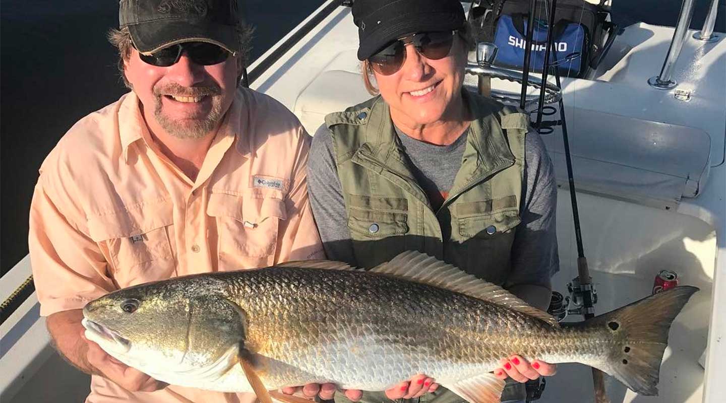 A couple holding bull redfish at the Inshore Fishing Charter