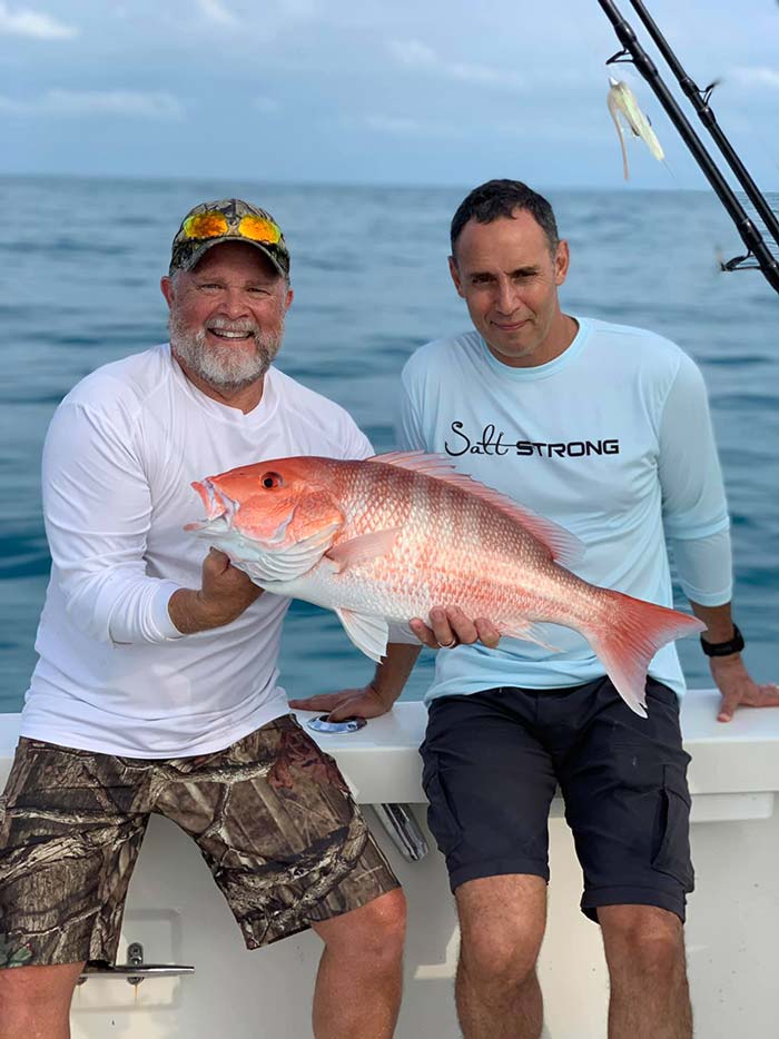 Men holding redfish caught on Daytona Beach Deep Sea Fishing trip