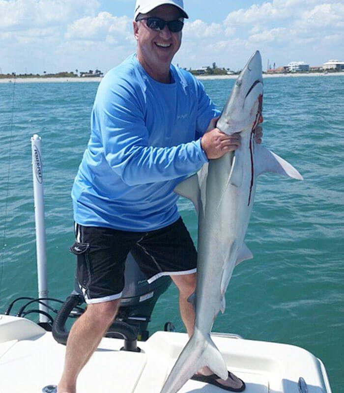 Man holding shark at Fin & Fly Fishing Charter