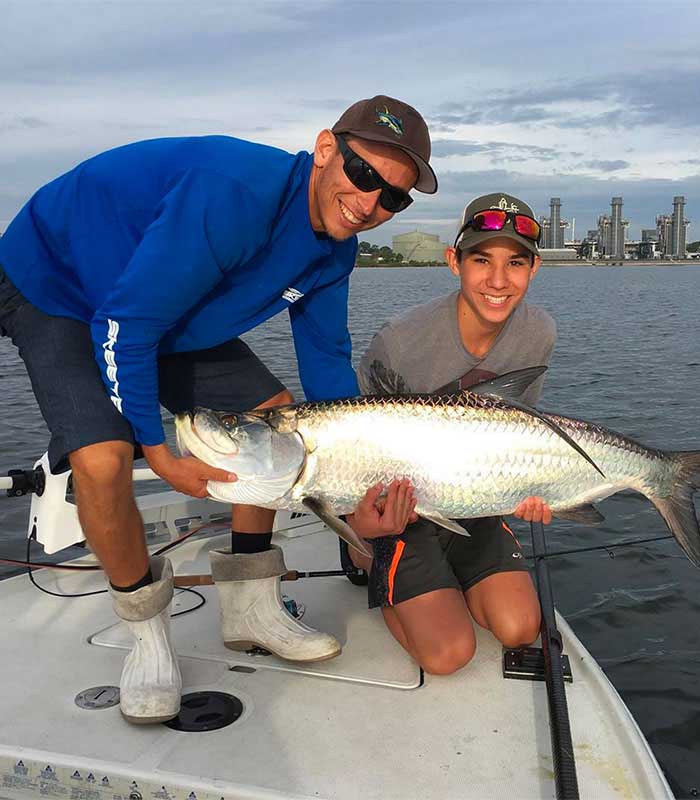 Orlando bucket list, captain and boy holding large caught Tarpon on bow of boat