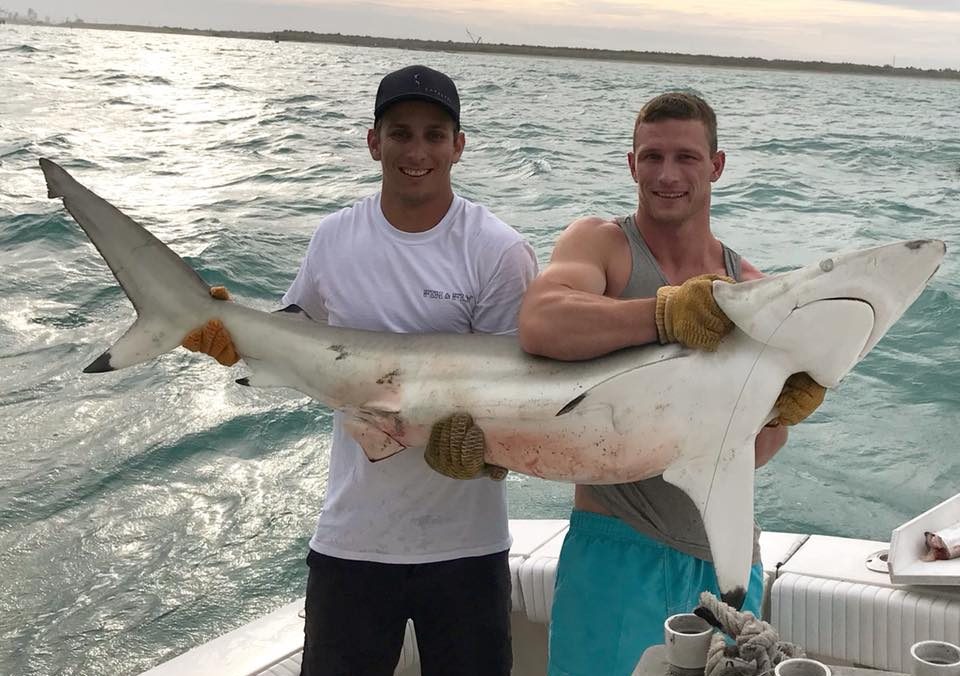 Central Florida two guys holding caught large shark, during deep sea fishing on boat