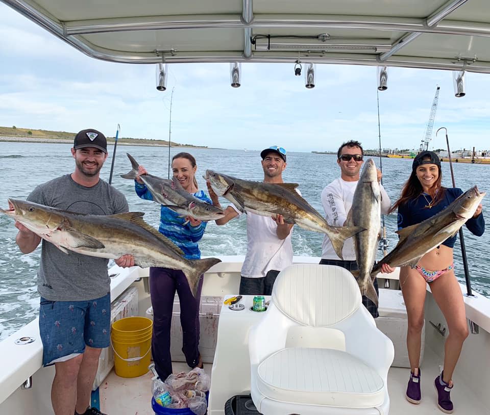group of five friends holding their caught fish on boat in Space Coast of Florida
