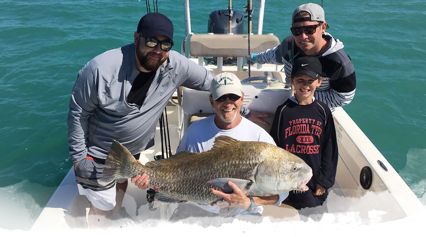 Angler and boy holding a large redfish on a Fin & Fly charter