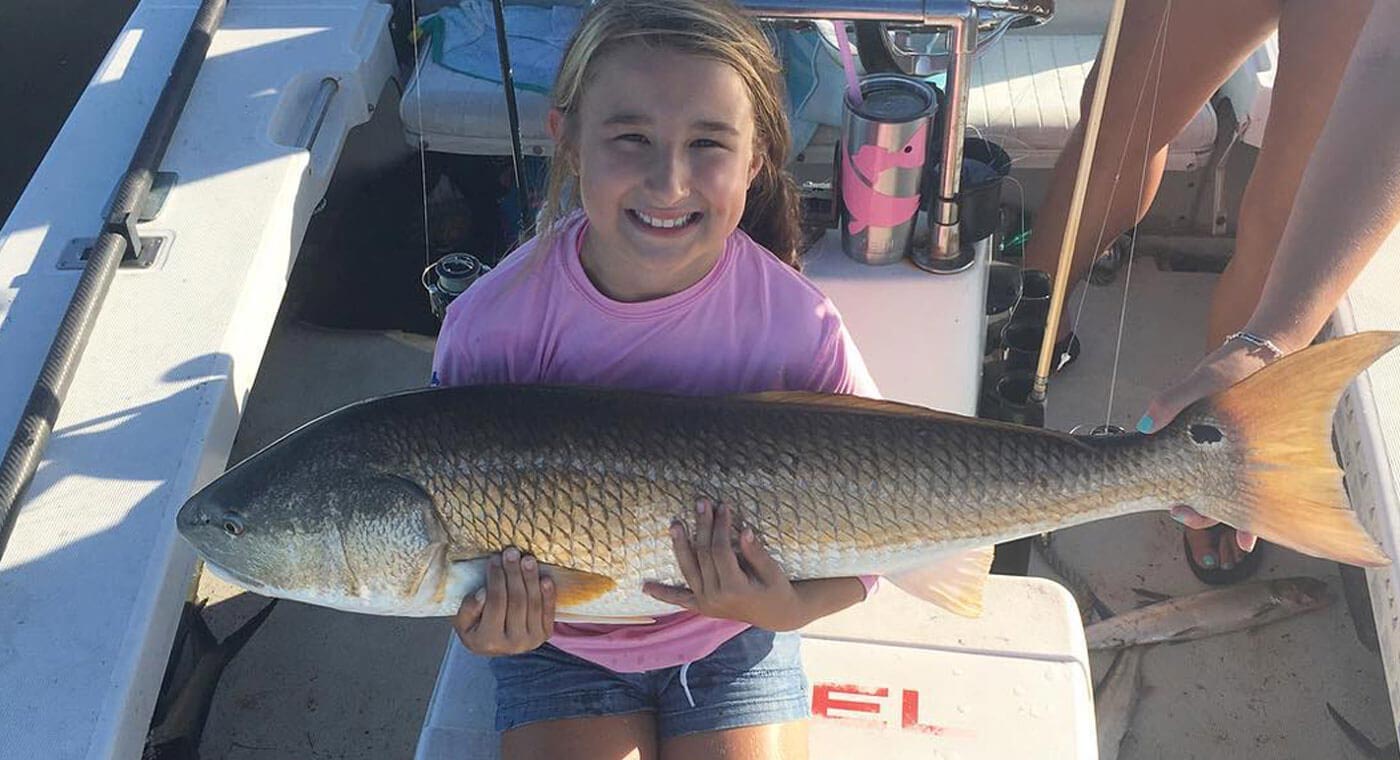 Girl holding a redfish caught on a river fishing charter