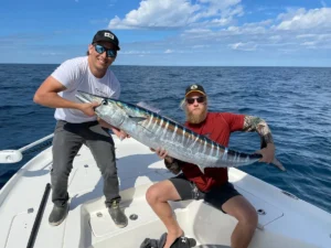 Anglers holding a wahoo on a private fishing charter offshore near Cocoa Beach Florida