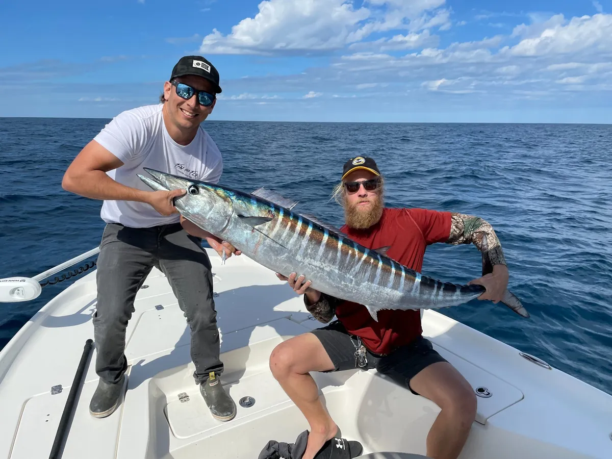 Two anglers holding a wahoo offshore of Cocoa Beach on a Fin & Fly charter; Florida wahoo have no minimum size
