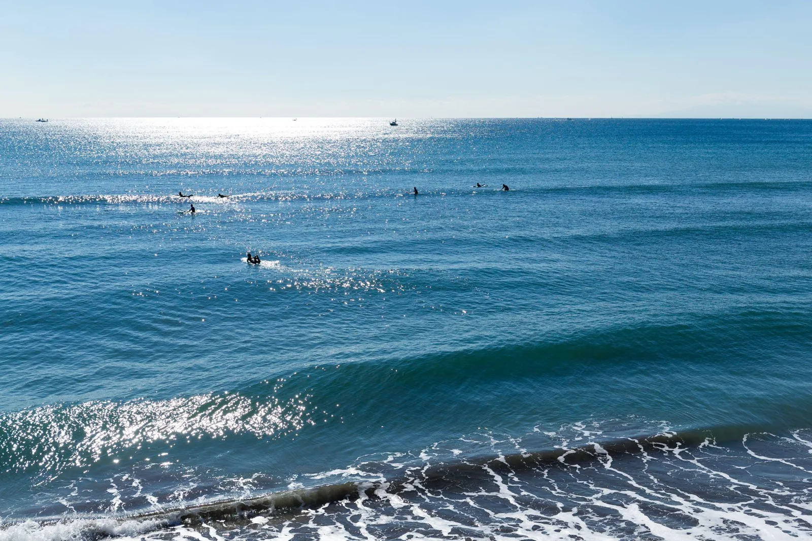 Surfers waiting on their boards past the breakers in clear blue water on a sunny day